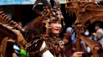 Seorang ilustrator muda sedang menyelesaikan karya seni digital yang mengadaptasi karakter mitologis Nusantara dengan sentuhan estetika kontemporer di studio kerjanya.