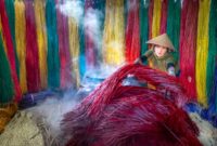 Seorang penenun perempuan di Sumba Timur sedang memintal benang kapas tradisional menggunakan alat tenun kayu non-mesin di pelataran rumah adat. Proses pembuatan kain tenun ini memanfaatkan pewarna alami dari tumbuhan lokal yang membutuhkan waktu pengerjaan hingga bertahun-tahun.