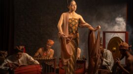 Seorang seniman visual menyelesaikan ilustrasi bertema cerita rakyat Nusantara yang memadukan teknik lukis tradisional dengan estetika desain grafis kontemporer.