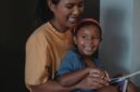 Momen hangat seorang ibu yang membacakan buku cerita rakyat Nusantara kepada buah hatinya sebelum tidur untuk melatih imajinasi dan memperkuat ikatan emosional keluarga.